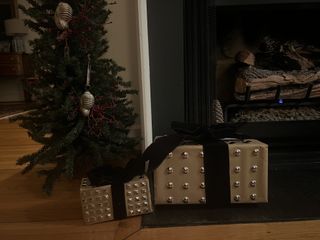 Two stud embellished christmas presents by a fireplace and a small Christmas tree